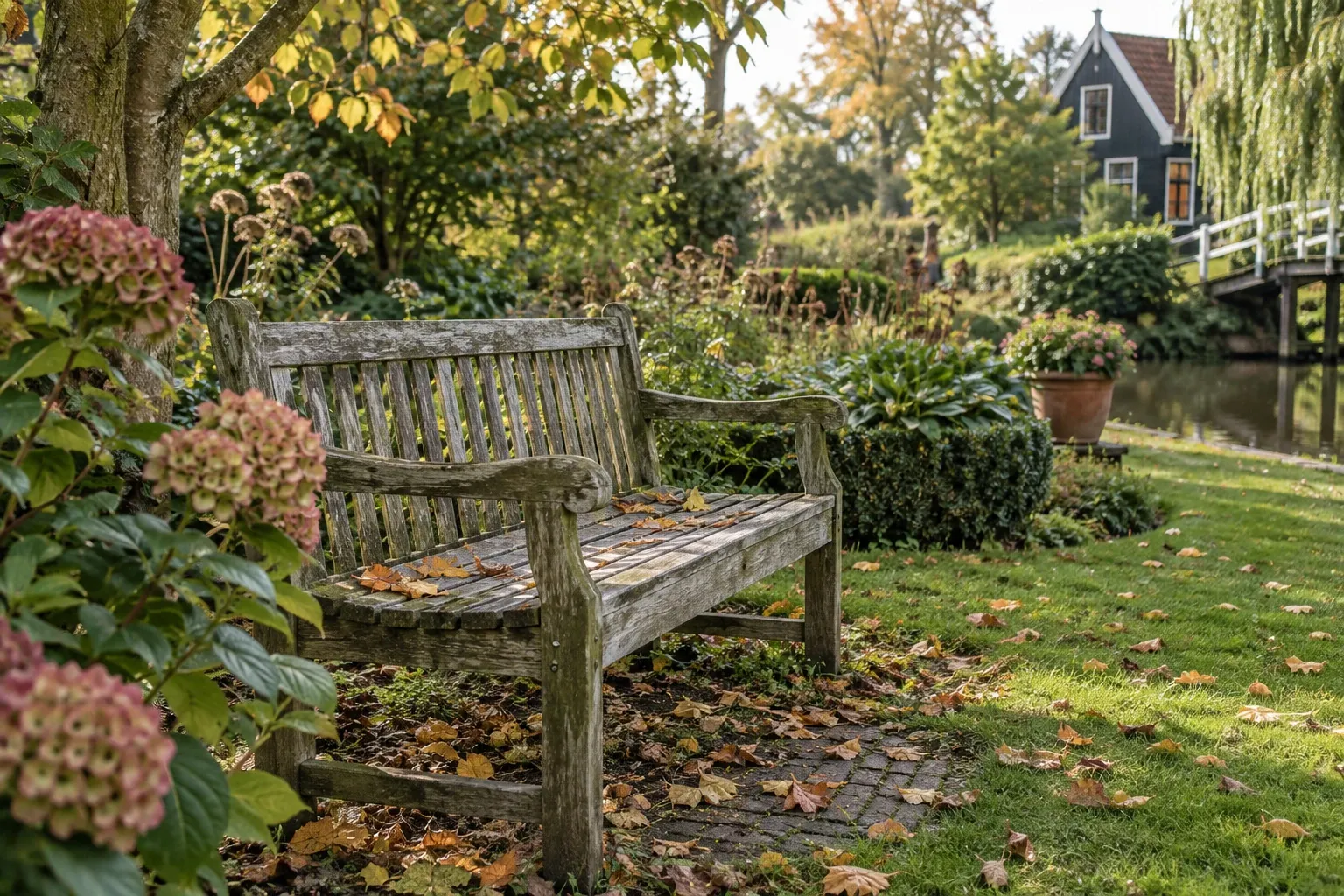 Verweerde houten tuinbank met herfstbladeren naast grachtenhuis en groenplantsoen